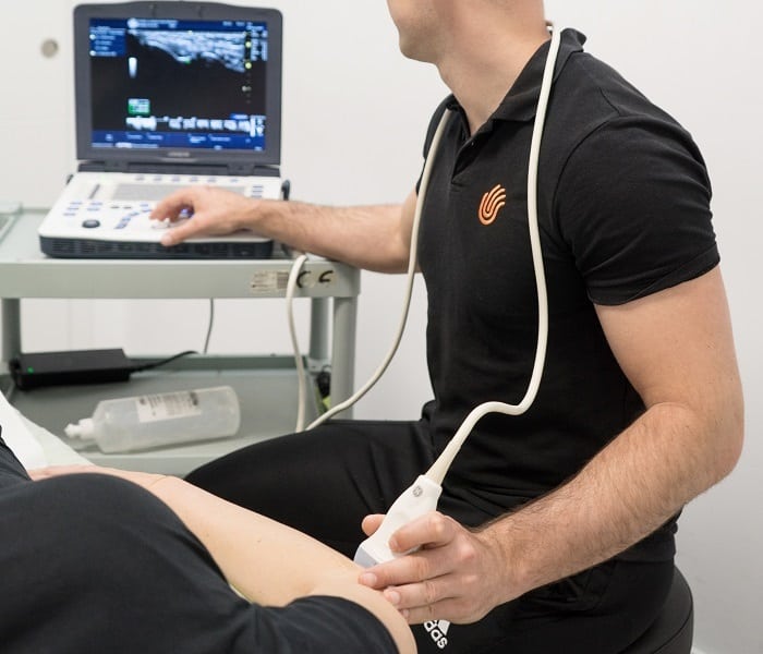 fisioterapeuta haciendo ecografia del codo de una paciente