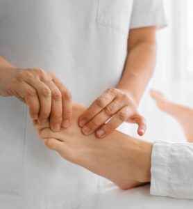 masaje podologico realizado por profesional de salud en pie de paciente en ambiente clinico luminoso
